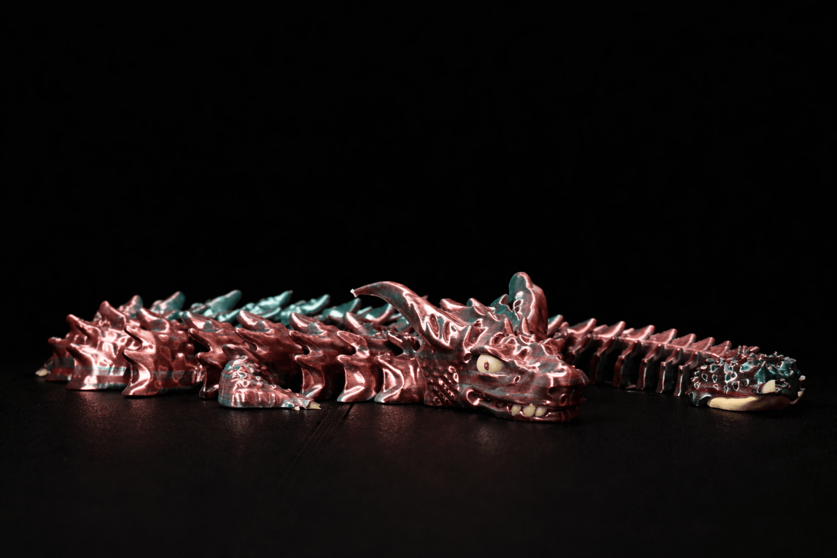 3D Druck Drache aus Kunststoff in metallischem Rot mit türkisfarbenen Akzenten, Hörnern und gegliedertem Körper