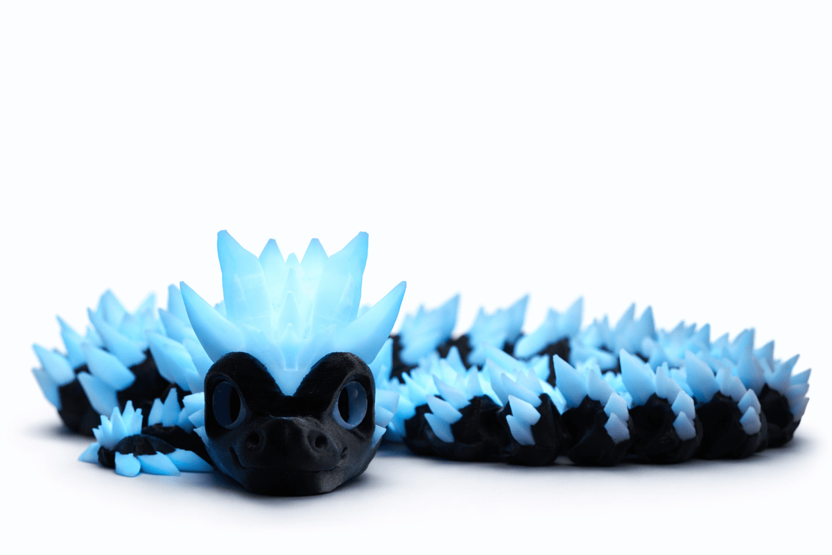 3D Druck Drache aus schwarzem Kunststoff mit hellblauen Stacheln, großer Kopfkrone und gegliedertem Körper