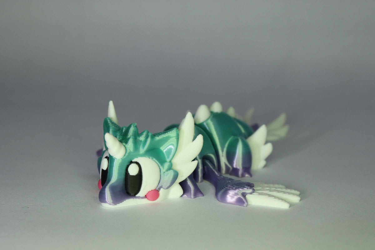 Drachenfigur ProtoDrache Auroria aus Kunststoff in Türkis und Violett mit großen Augen, weißen Hörnern und gegliedertem Körper
